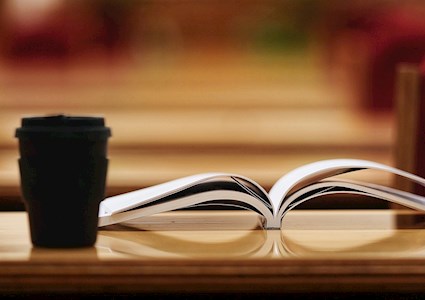 coffee mug on top of a table piled with books