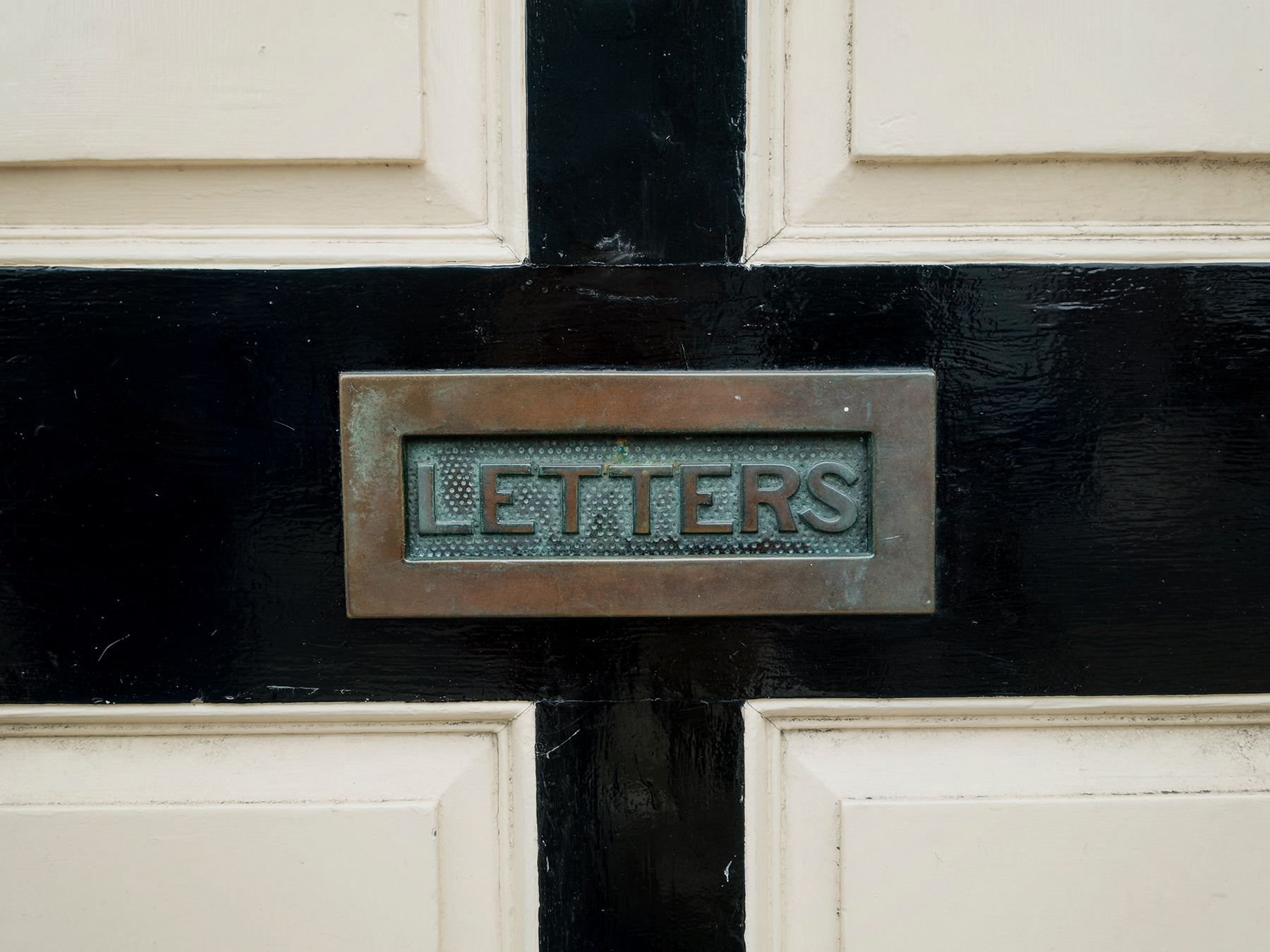 Photograph shows a door with a brass opening to insert mail into.