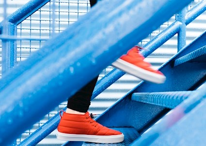 woman wearing bright red sneakers walking up bright blue stairs. there are raindrops on the stairs.