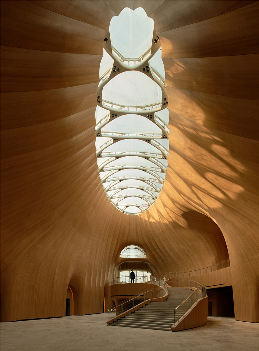 Irregular-shaped roof with a skylight in the middle. There is a monumental staircase within the multistory lobby. 