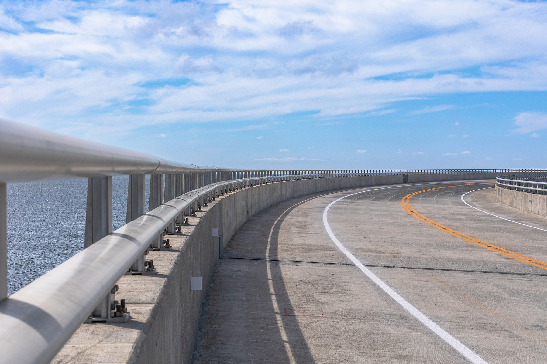 A roadway with dividing lines and a concrete barrier is shown. 