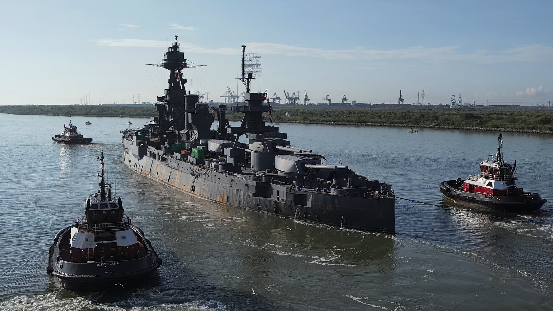 Surrounded by a small flotilla of tugboats and other escorting vessels, the Texas was towed through the Houston Ship Channel in late August. (Image courtesy of Captiv Creative)