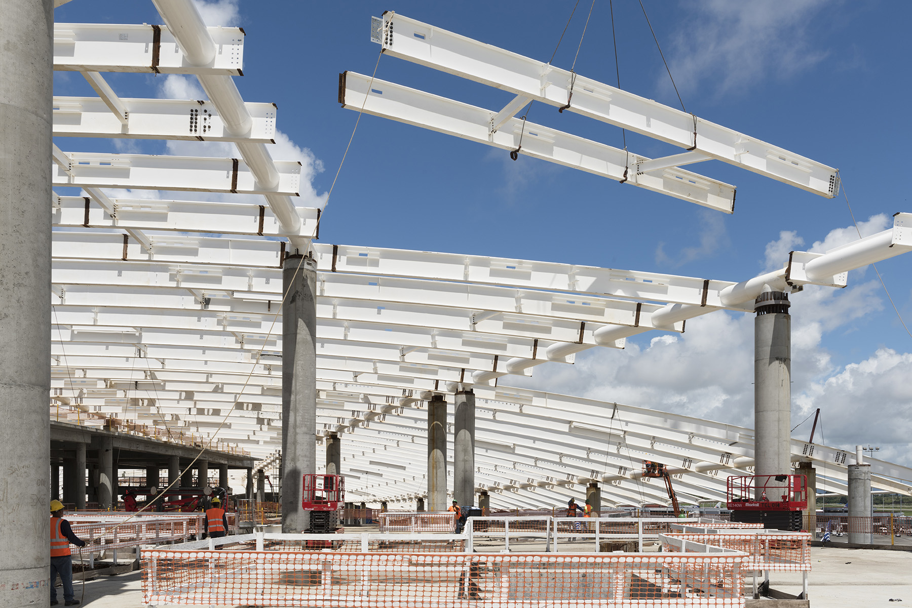 Photograph shows the white metal beams that form the roof of an airport terminal.