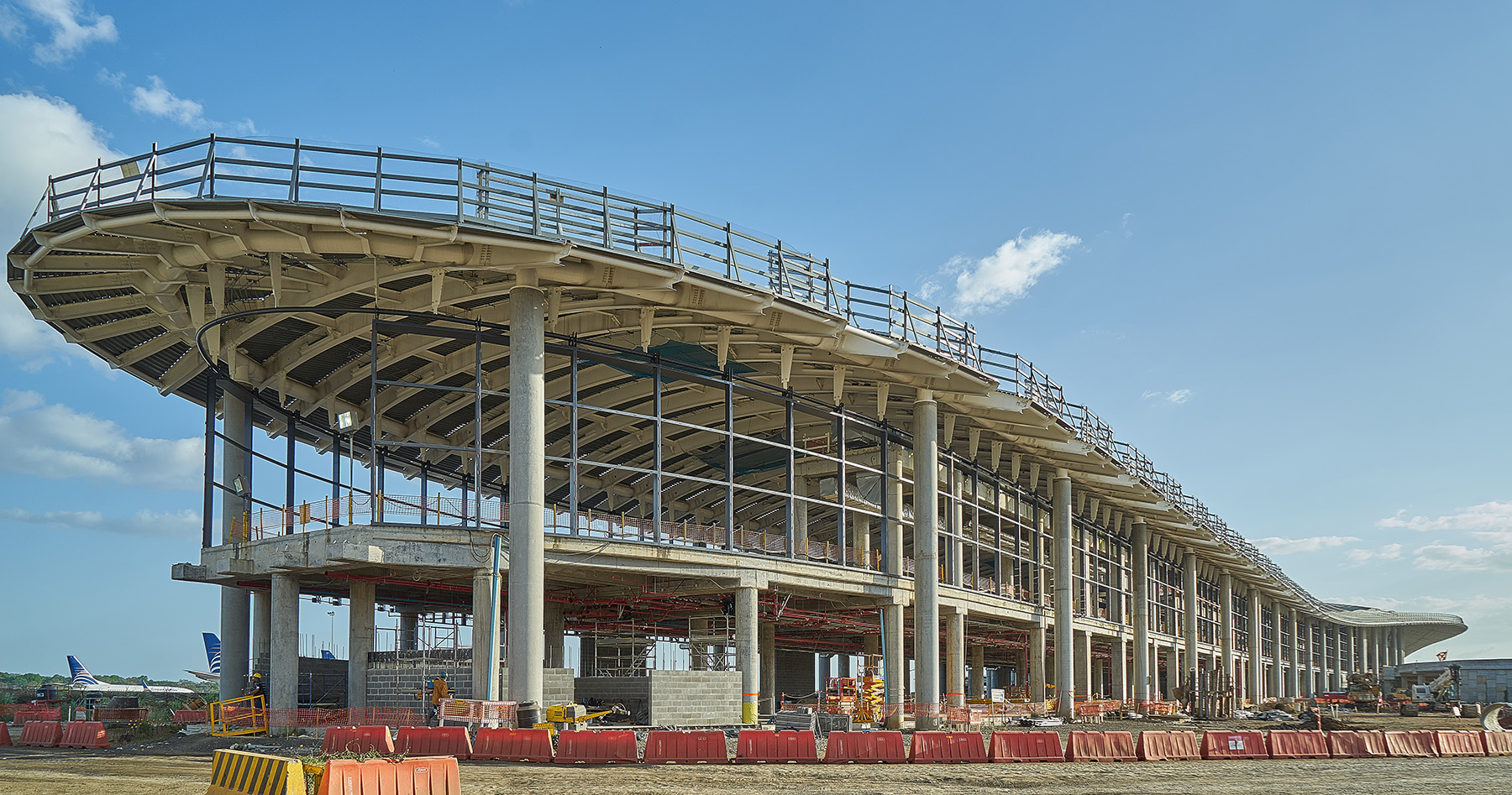 An in-construction shot of a new airport terminal showing foundation and roof supports among other objects.