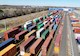 Multiple shipping containers in different colors sit in a shipping yard. 