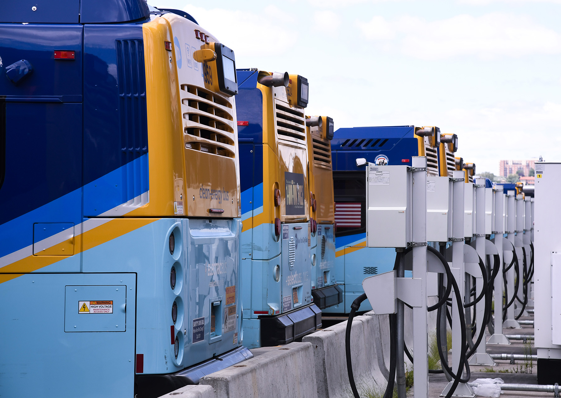 A row of buses sitting in front of charging stations.