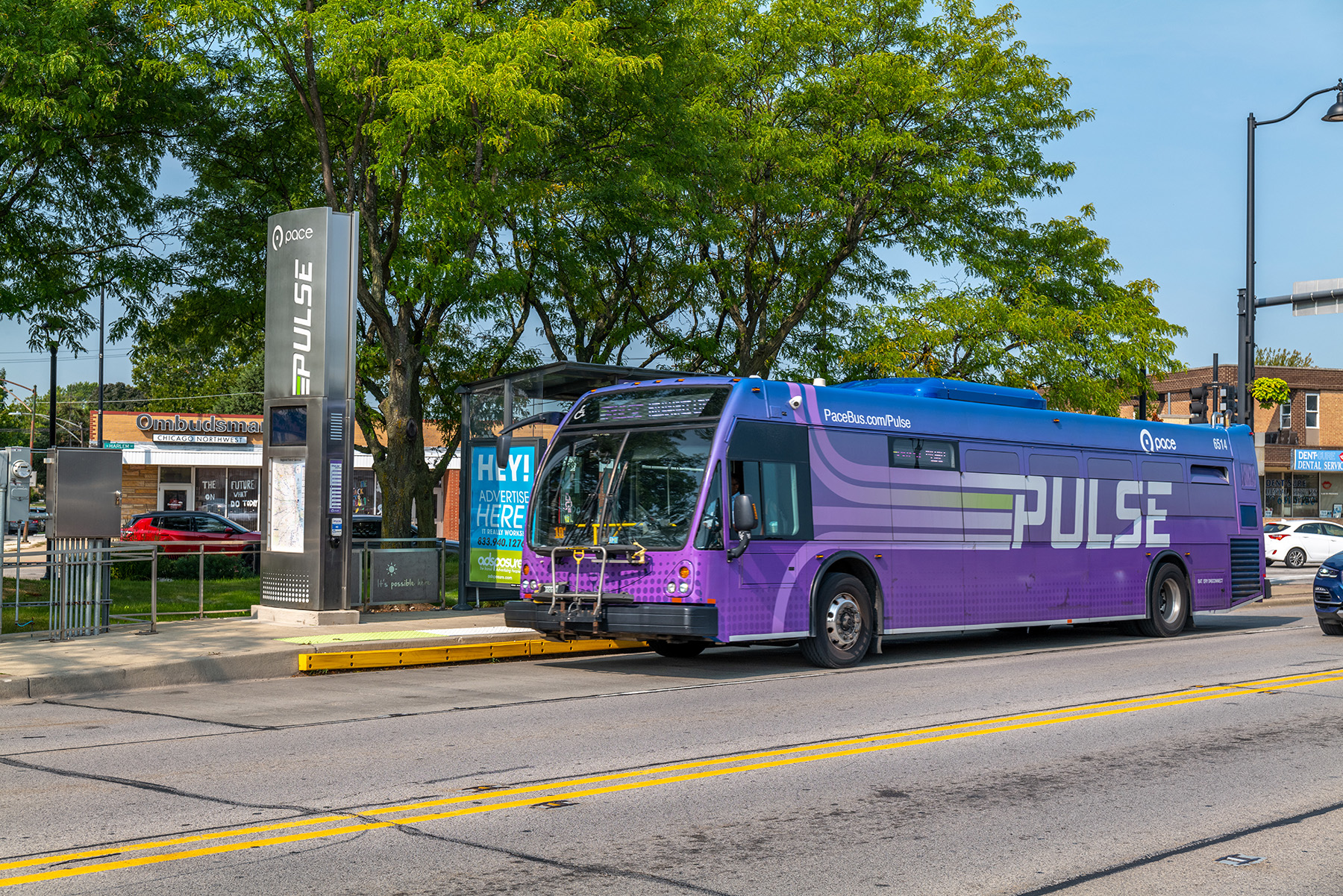 A purple bus travels down the road.