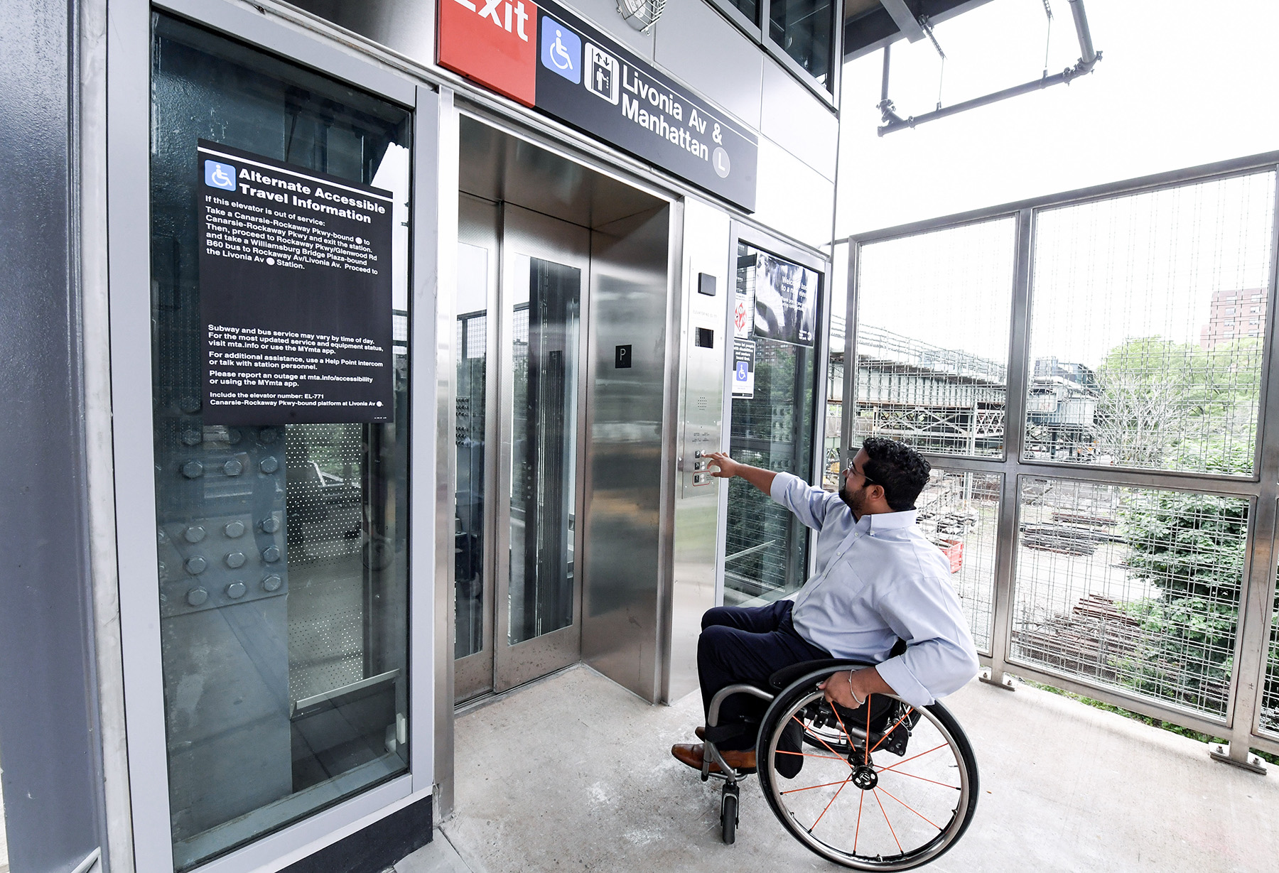 Man in a wheelchair pushes a button for the elevator.
