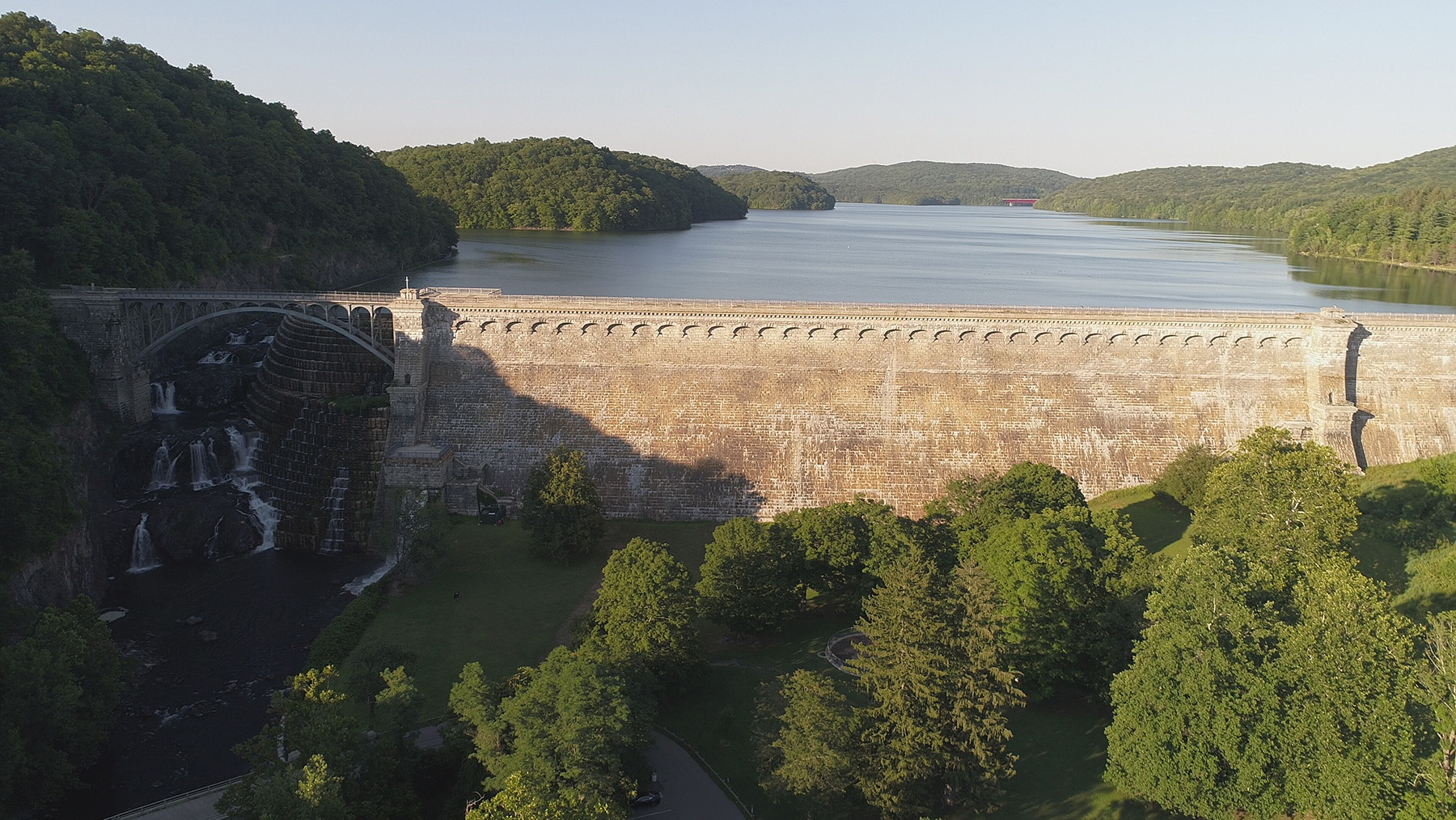 Photo shows a large stone wall that contains water.