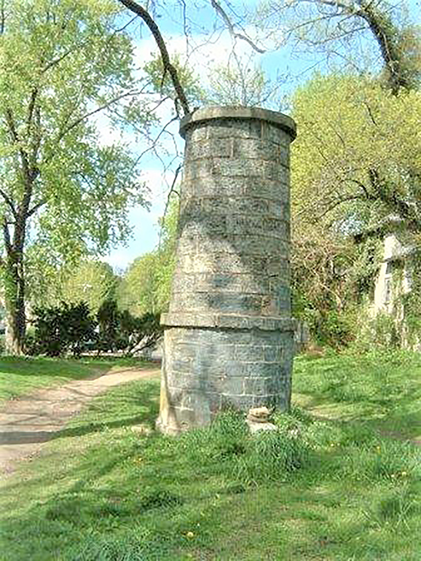 A tall, round structure set amid a grassy area.