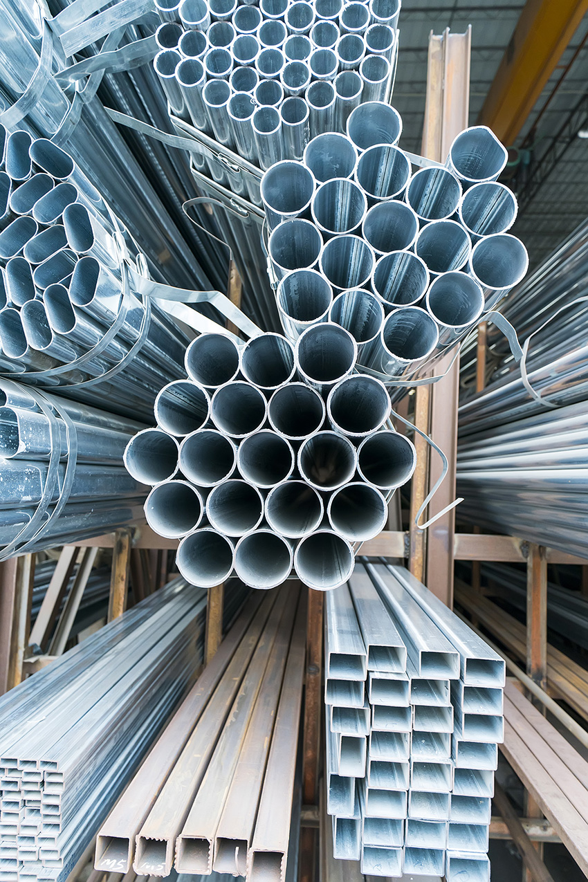 Steel tubes of various shapes are stacked on top of one another on wooden shelves.