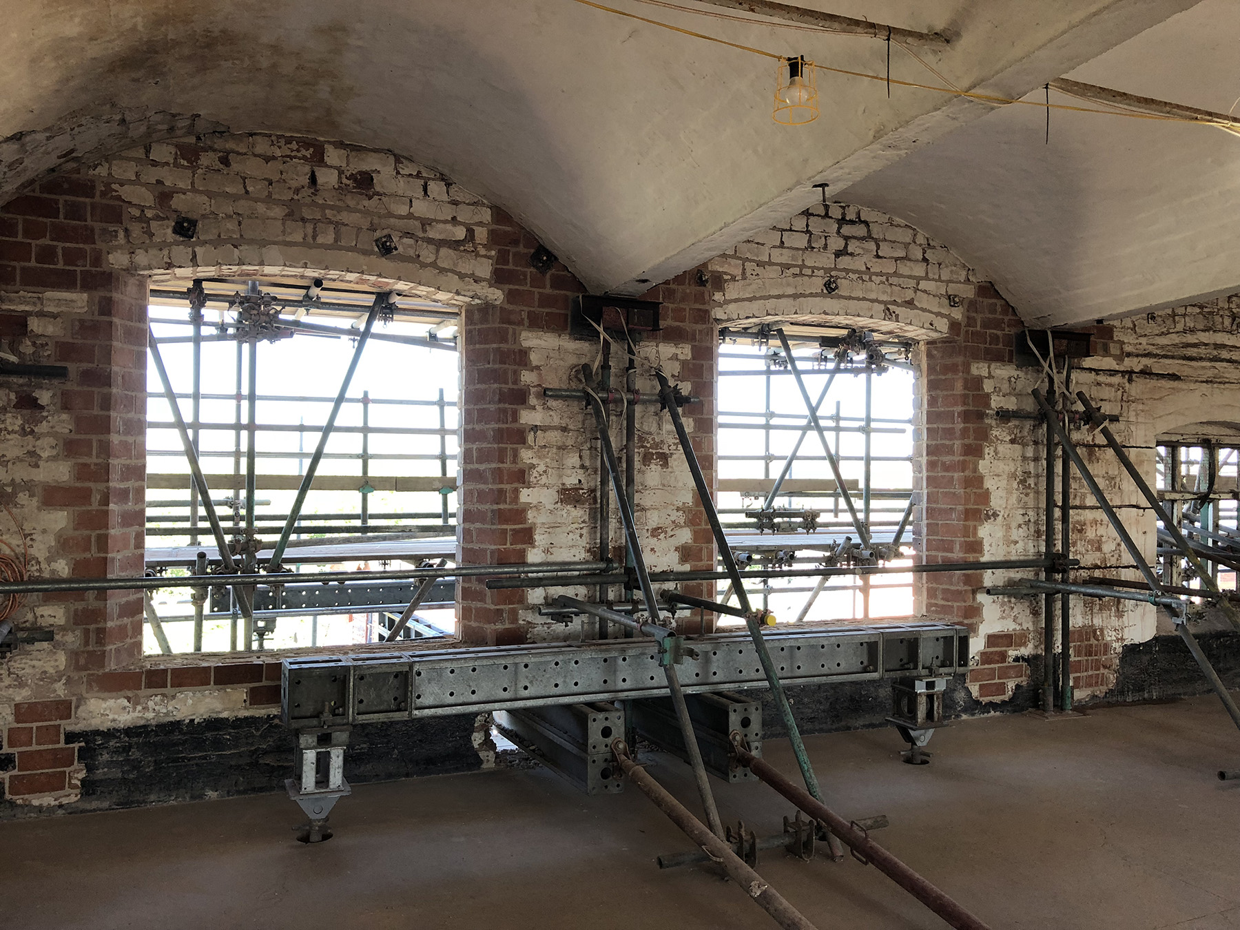 Scaffolding sits inside large windows with an arched ceiling above them.