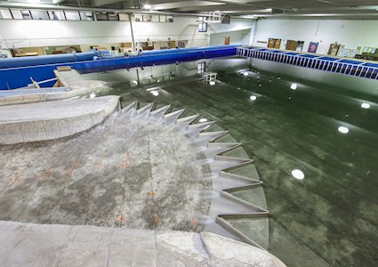 A large-scale model is shown sitting within a large rectangular structure with water in it. 