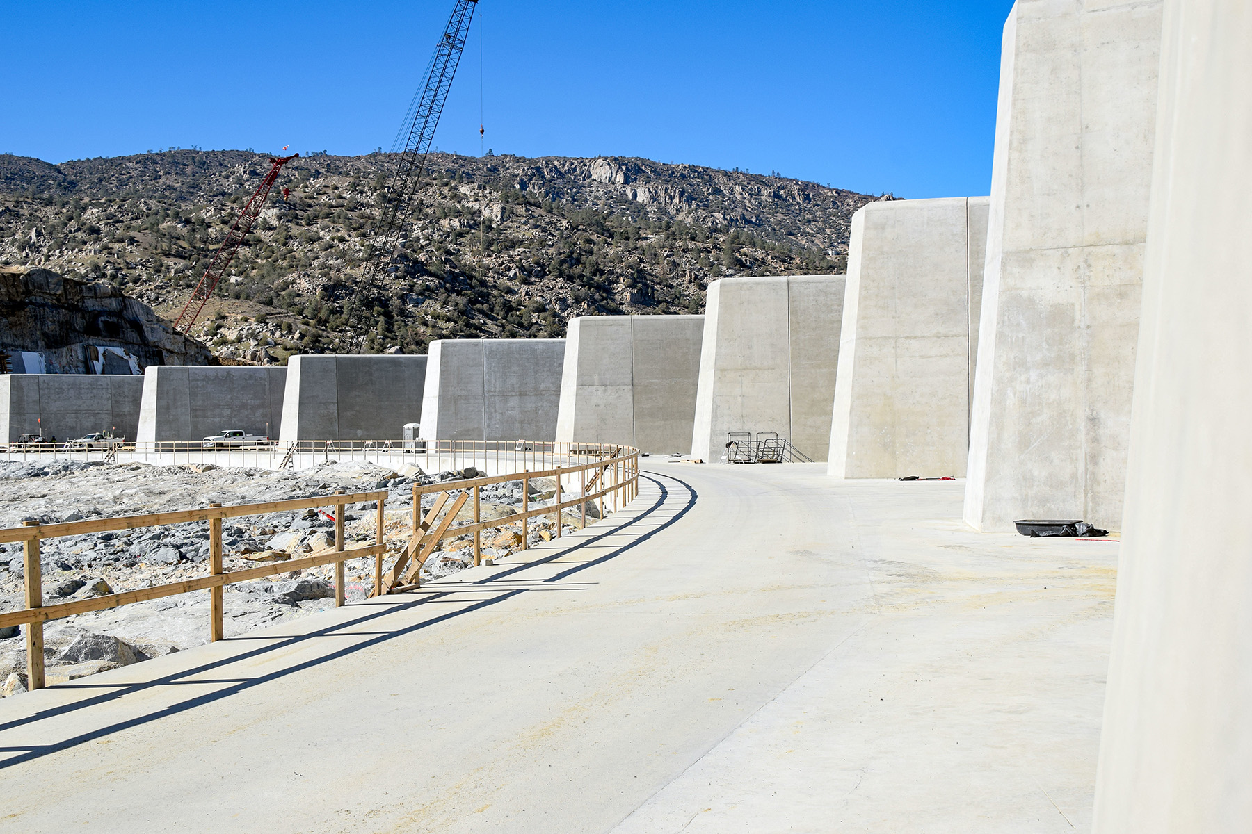 Tall, white walls stacked in a row sit in a large white slab. A crane is in the distance.