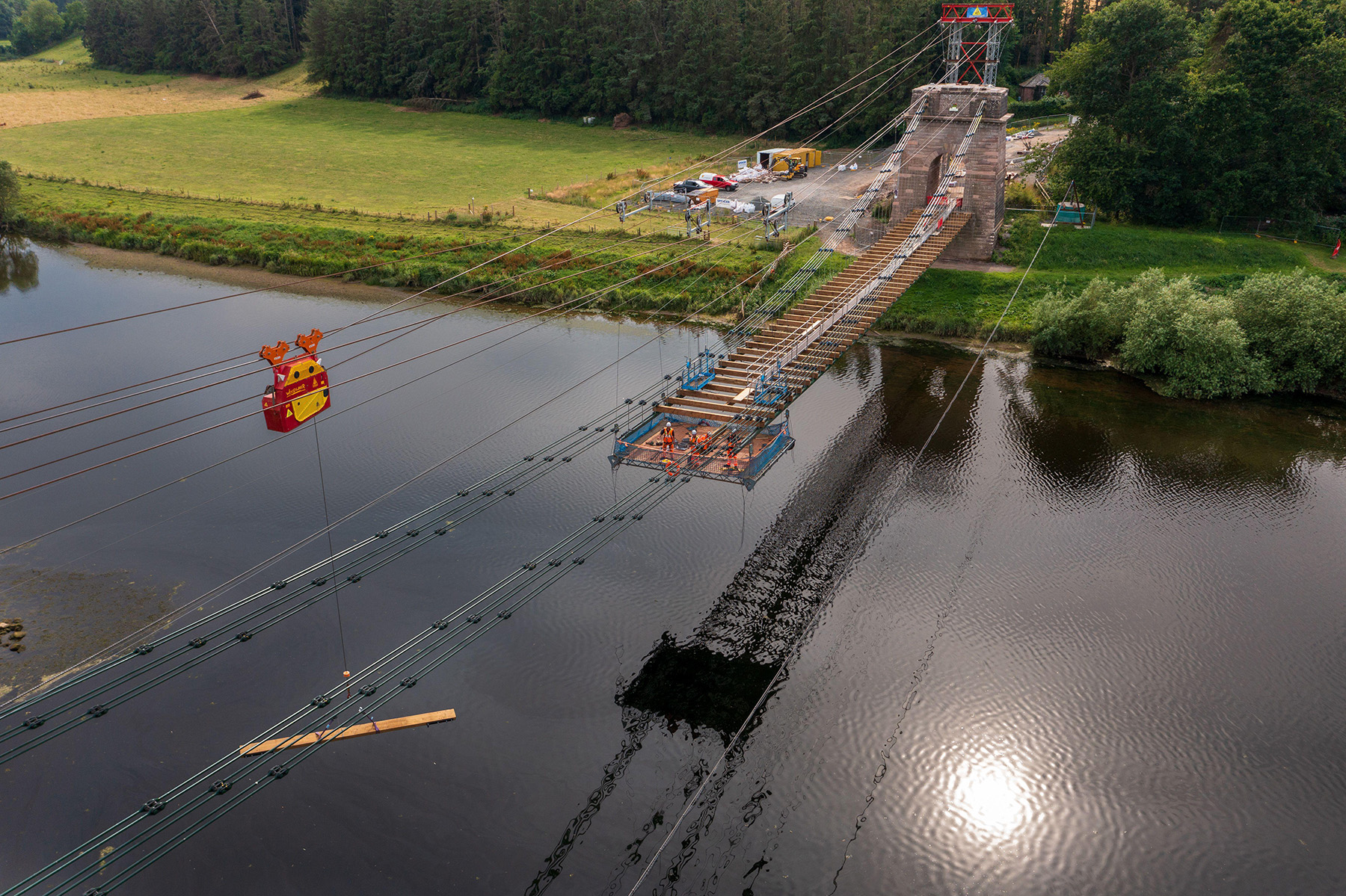 Work crews are replacing a bridge deck. They are suspended below the deck they are replacing.