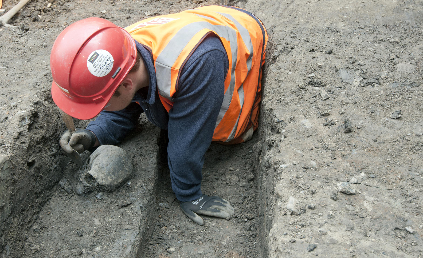 An archaeologist works to excavate a skull along the side of an ancient Roman road near Liverpool Street ticket hall. (Image courtesy of Transport for London)