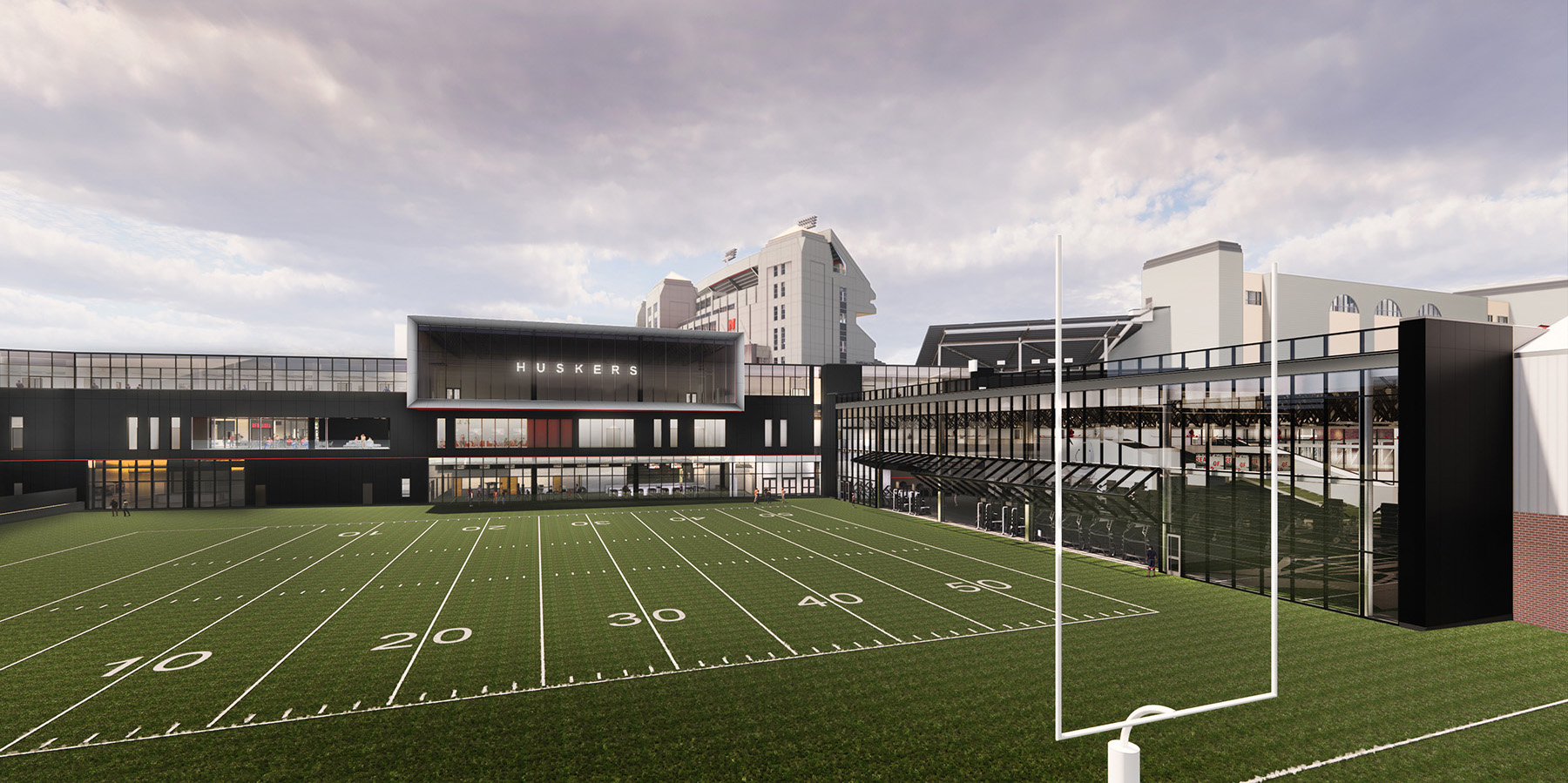 Rendering shows the backside view of a new building with a practice football field in the foreground. 