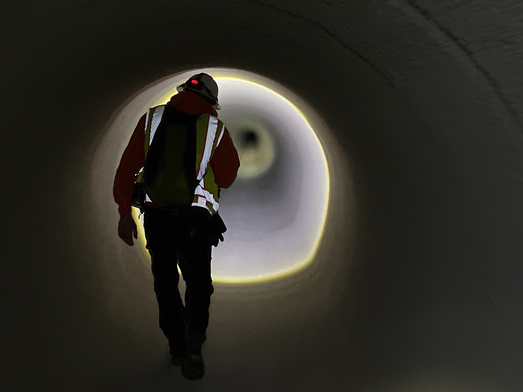 A worker conducts the final visual inspection of the rehabilitated section of the Red Mountain Tunnel. (Image courtesy of Michels Trenchless Inc