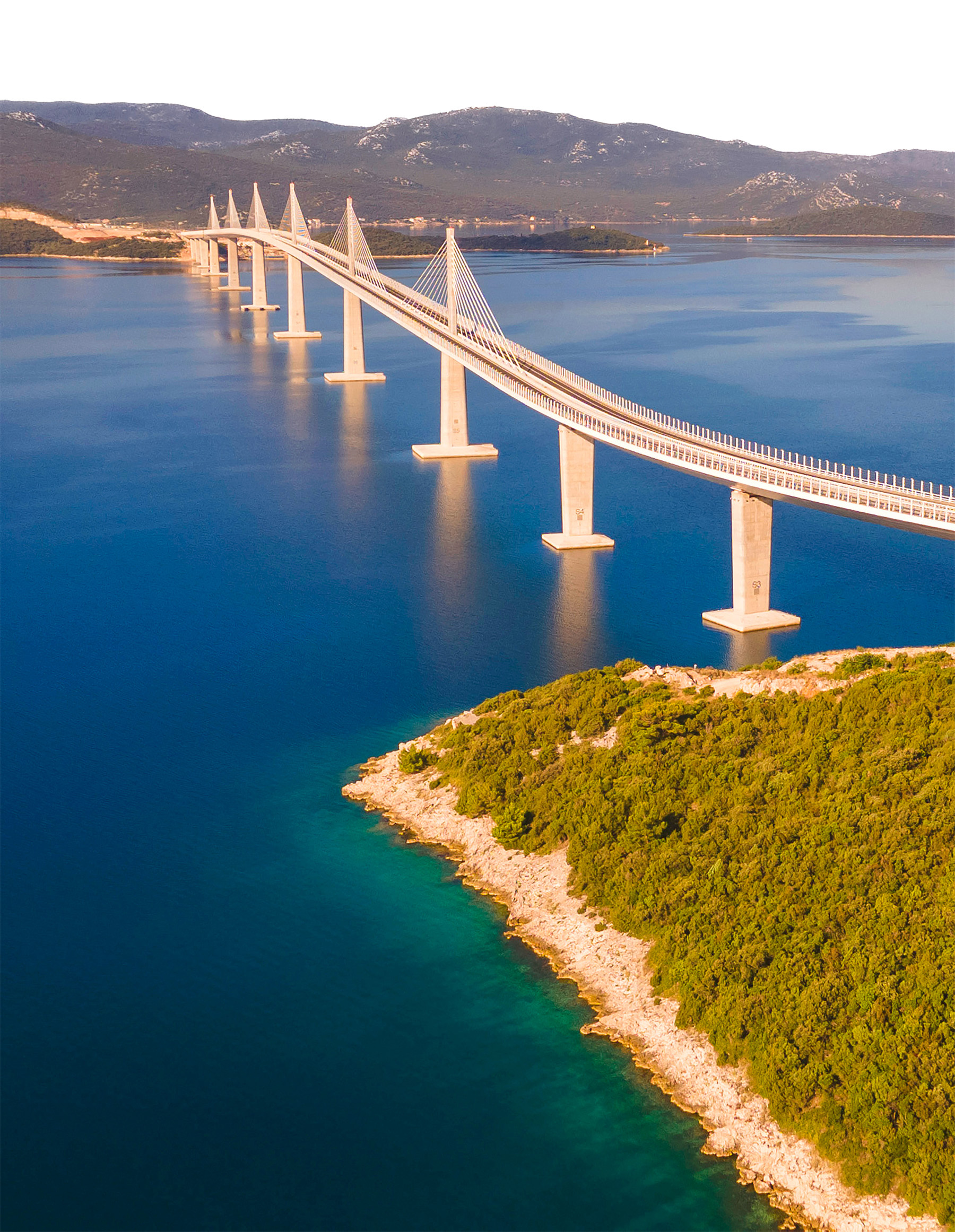 A bird’s-eye view shows the bridge spanning across the channel, with blue water below. 