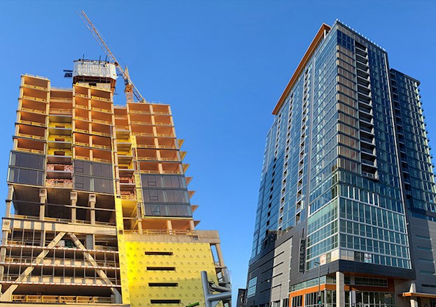 Left photo shows the construction of a high-rise building made of timber and other materials. Right photo shows the construction of a high-rise building made of timber and other materials.