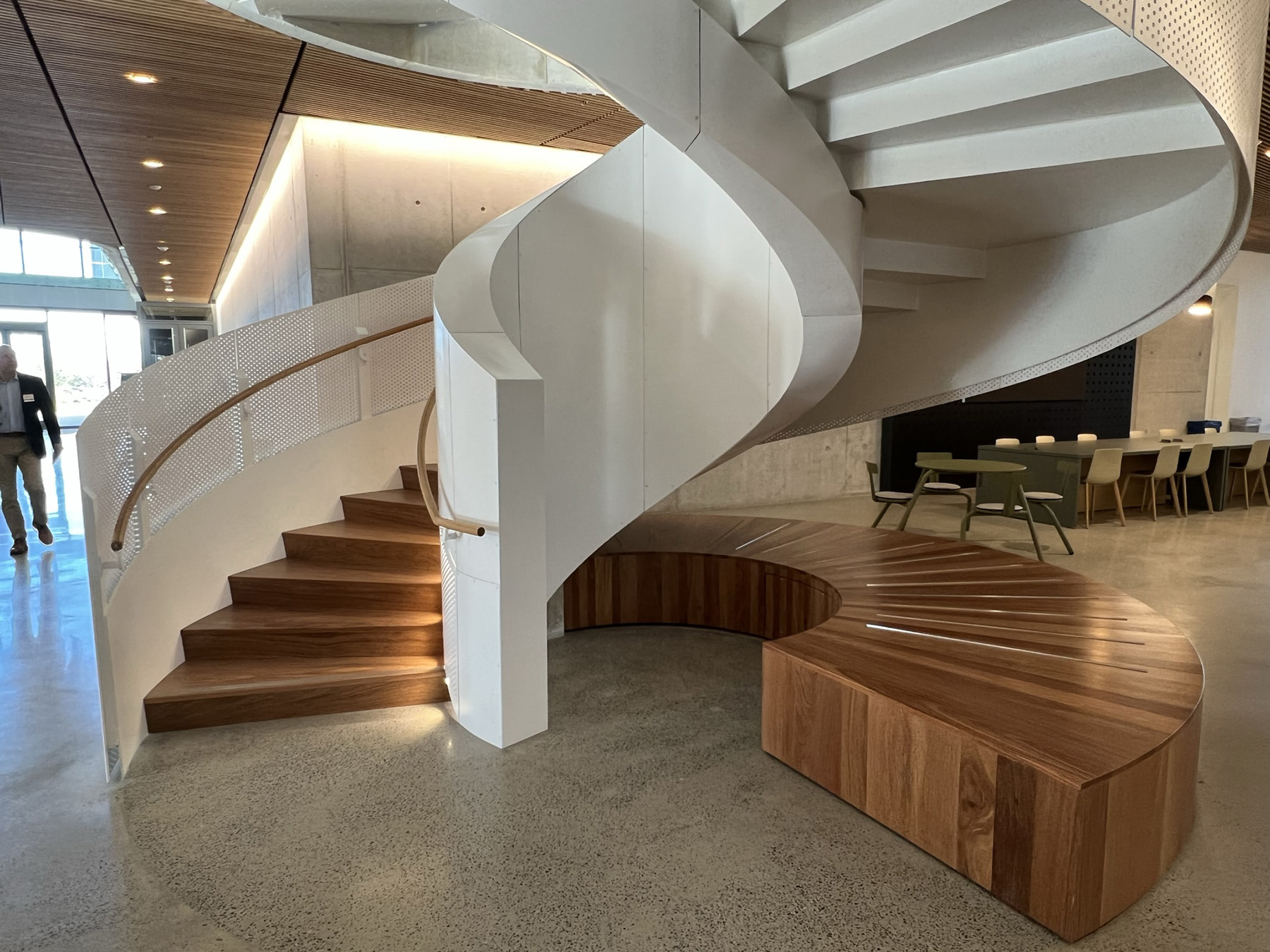 The white steel staircase with wood at its base spirals in the center of the building. 