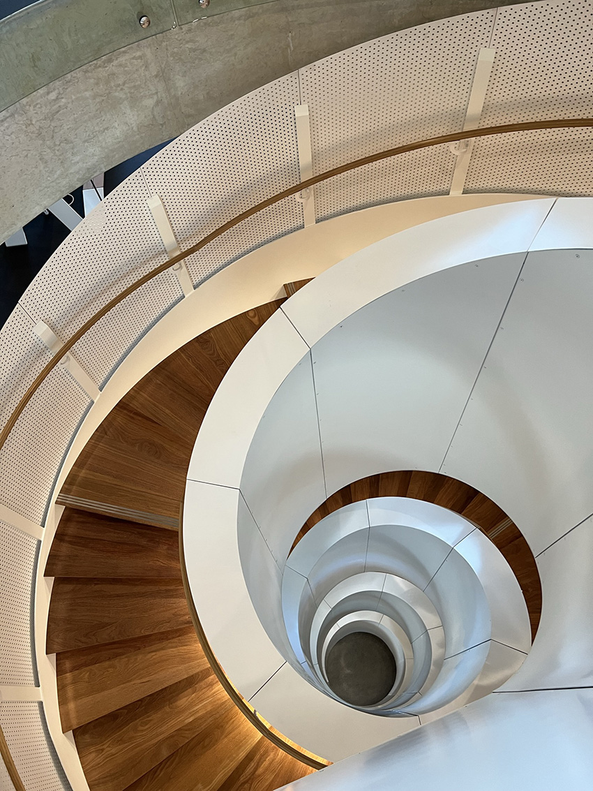 The spiral staircase is seen from the top. The spiral loops down four floors and shows the floor in a center circle. 