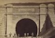Men stand outside a railroad tunnel. 