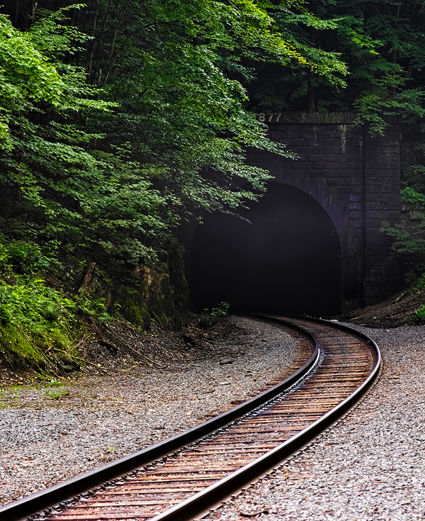 Curving train tracks emerge from a tunnel. 