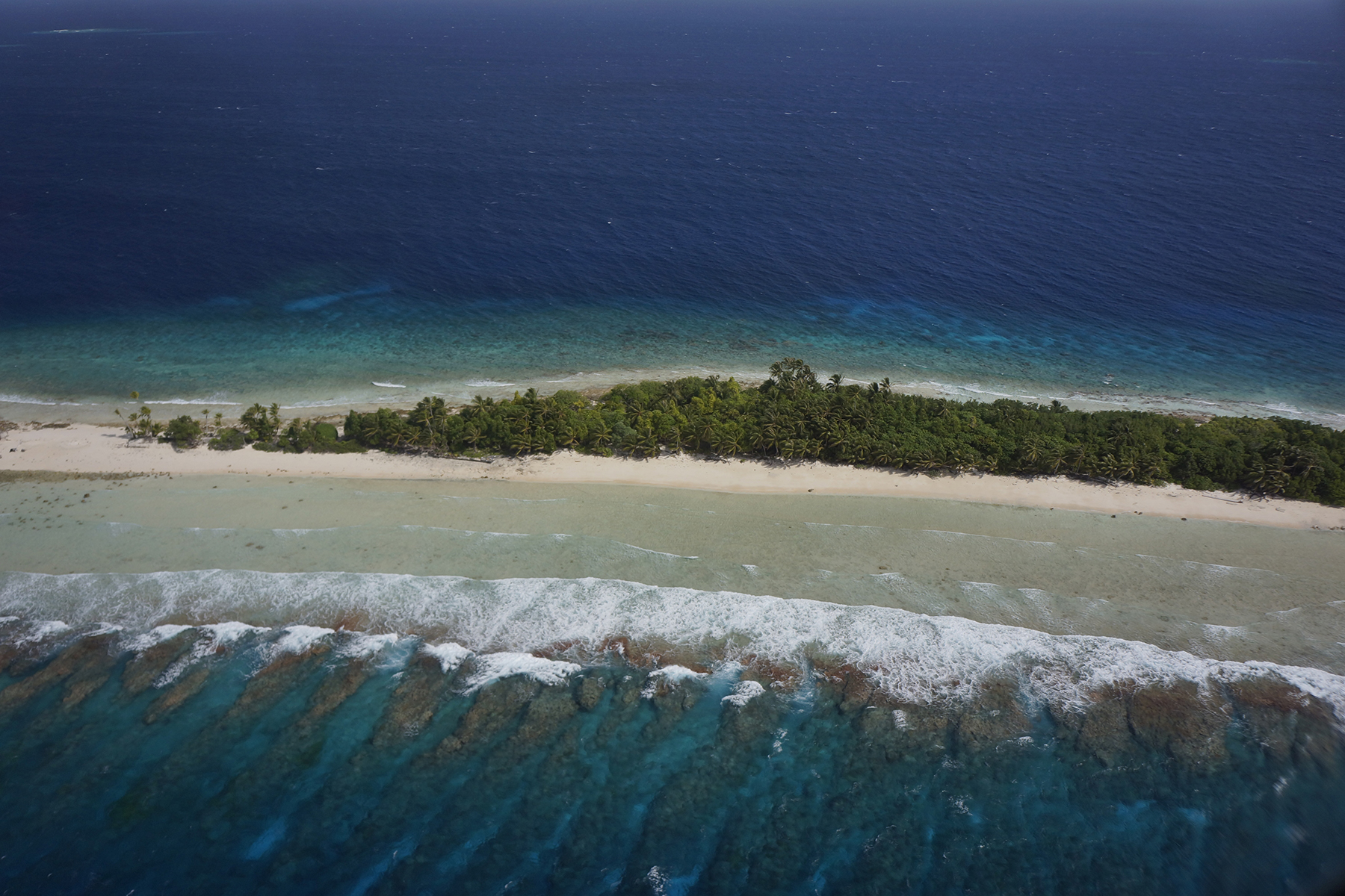 aerial overview of low-lying islands and corals reefs