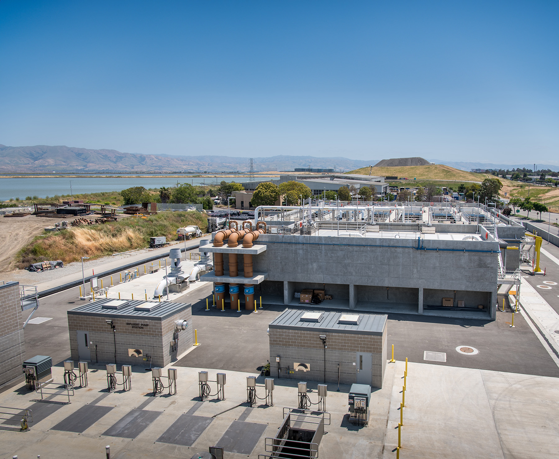 A multibuilding campus sits next to a filled landfill and large body of water. 