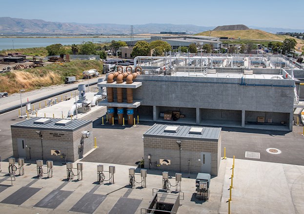 A multibuilding campus sits next to a filled landfill and large body of water.