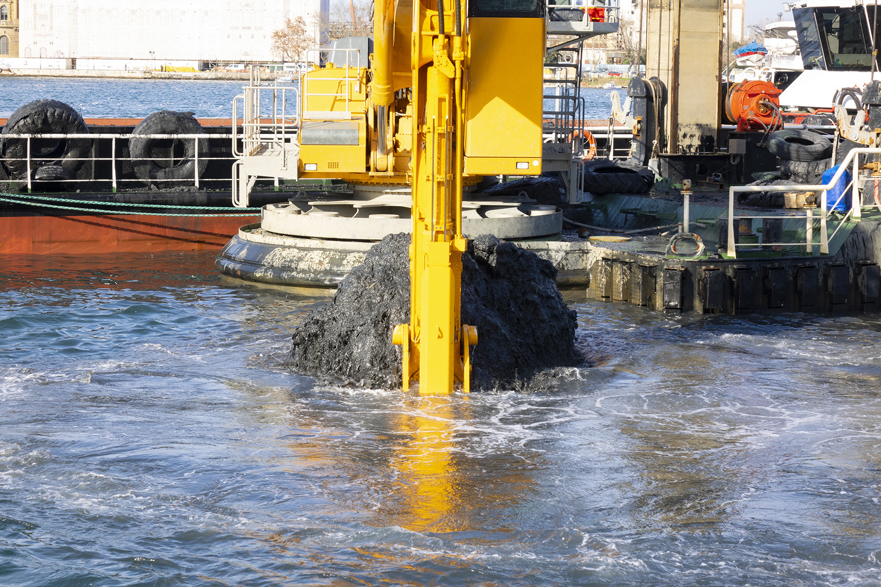 Sediment is being dredged from a body of water by large equipment. 