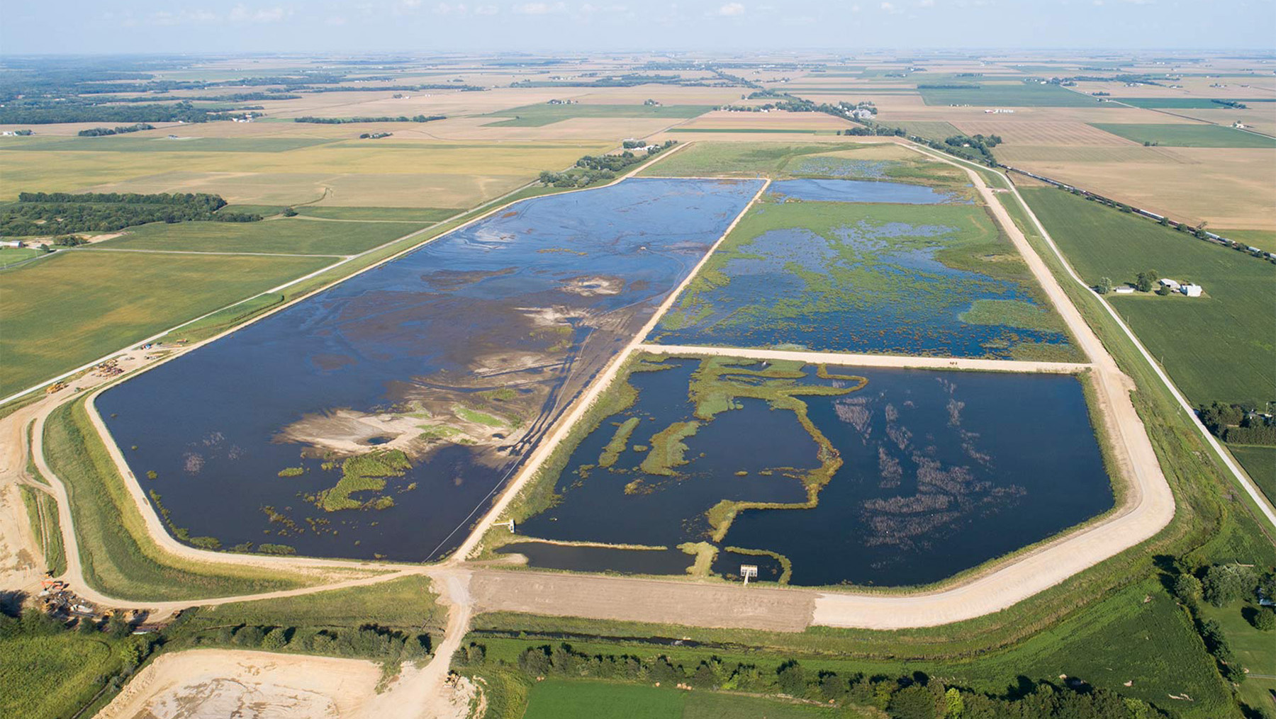 Image shows a water and sediment storage basin located in a field. 