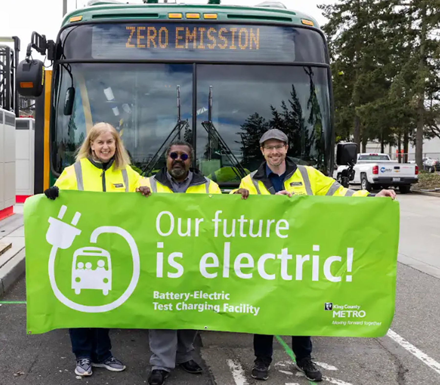 people smile with signs promoting electric buses