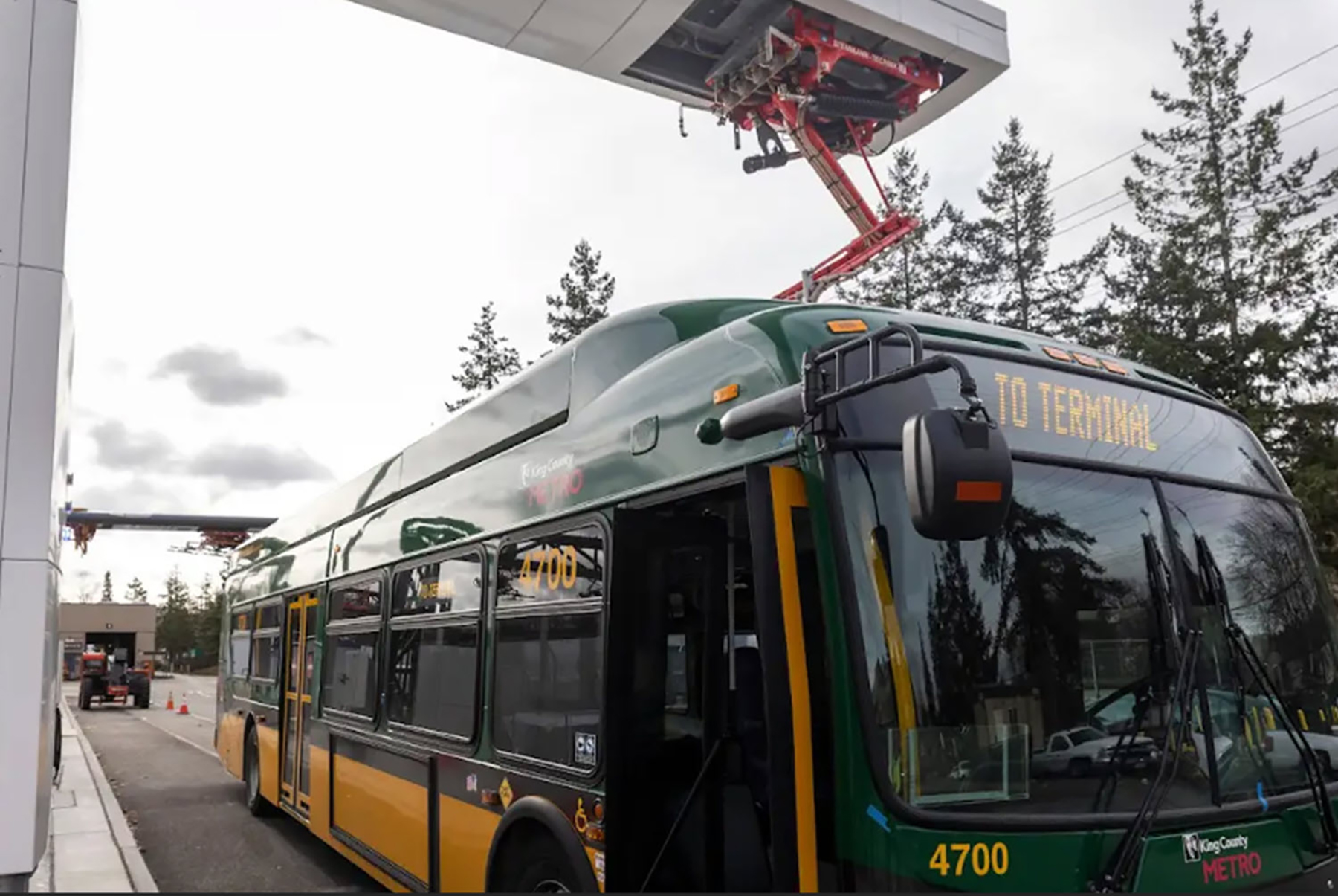 An electric bus connects to an overhead pantograph 