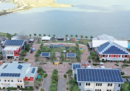 aerial picture of development featuring solar panels on roofs and body of water