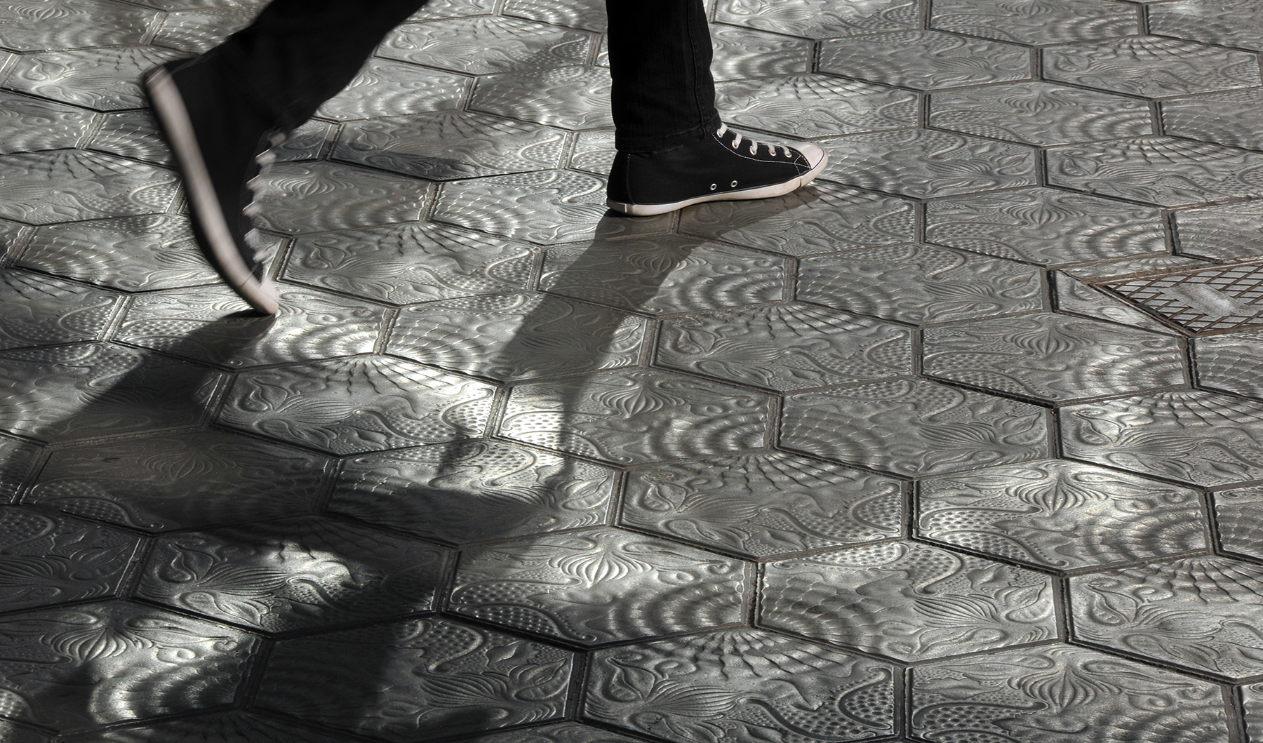 Image shows a person walking on hexagon-shaped tiles. 