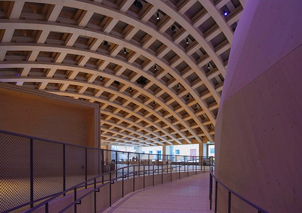 The interior of the Wisdome Stockholm depicts the crisscrossing roof beams and the edge of the domed arena.