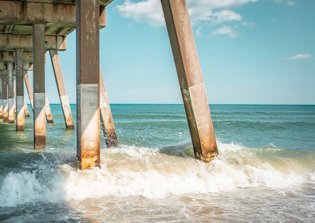 The ocean splashes around concrete piers.
