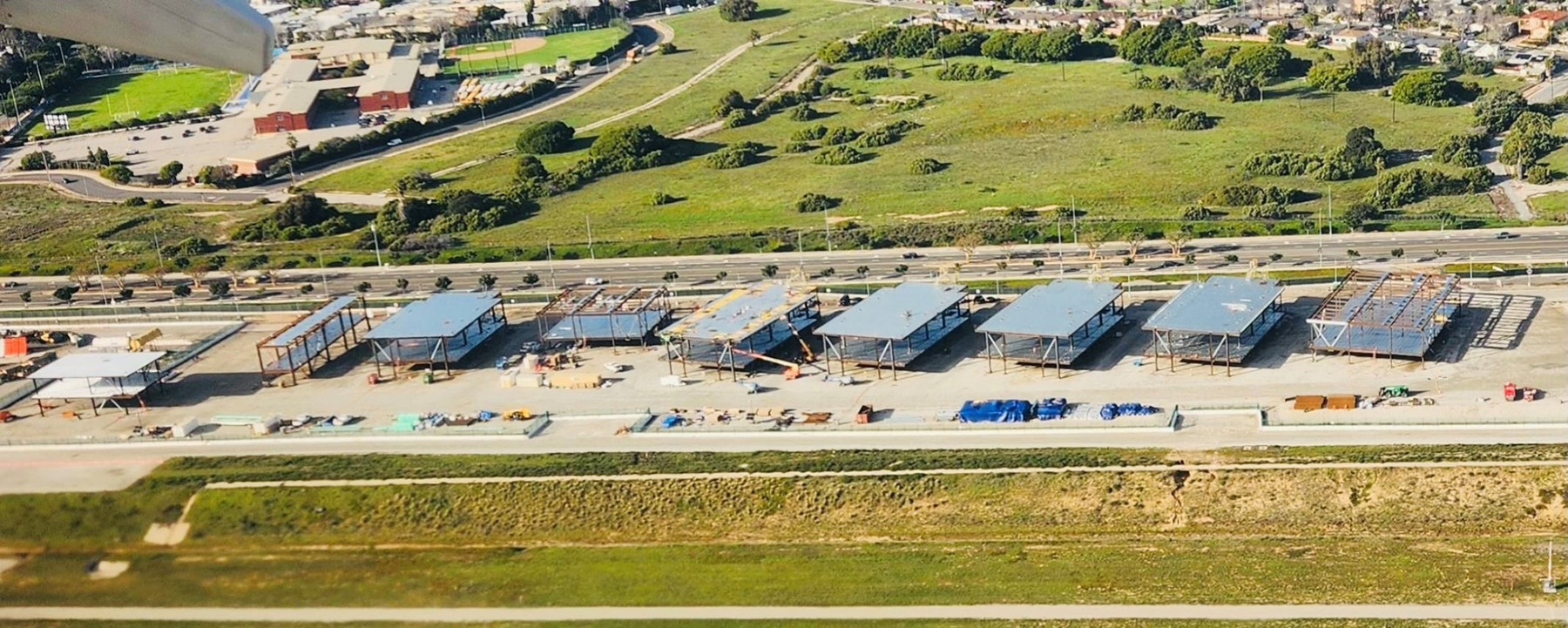 Segments at various stages of construction, some without walls and roofs, are lined up side by side off-site. 