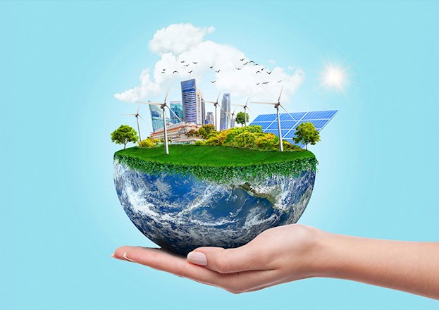 Image shows a woman’s hand holding half the earth. The top of the Earth is covered in green grass and plants. A cityscape with with windmills in the foreground and background can also be seen.