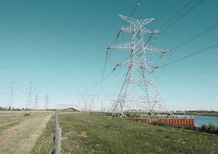Transmission towers and wires stretch across the land, including one large prominent tower.