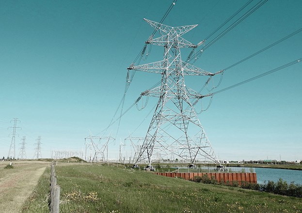 Transmission towers and wires stretch across the land, including one large prominent tower.