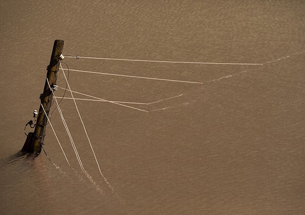Image shows a power line structure almost submerged in water.