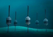 Rendering shows five cylinder-shaped pods stuck on poles and inserted into the sea floor.