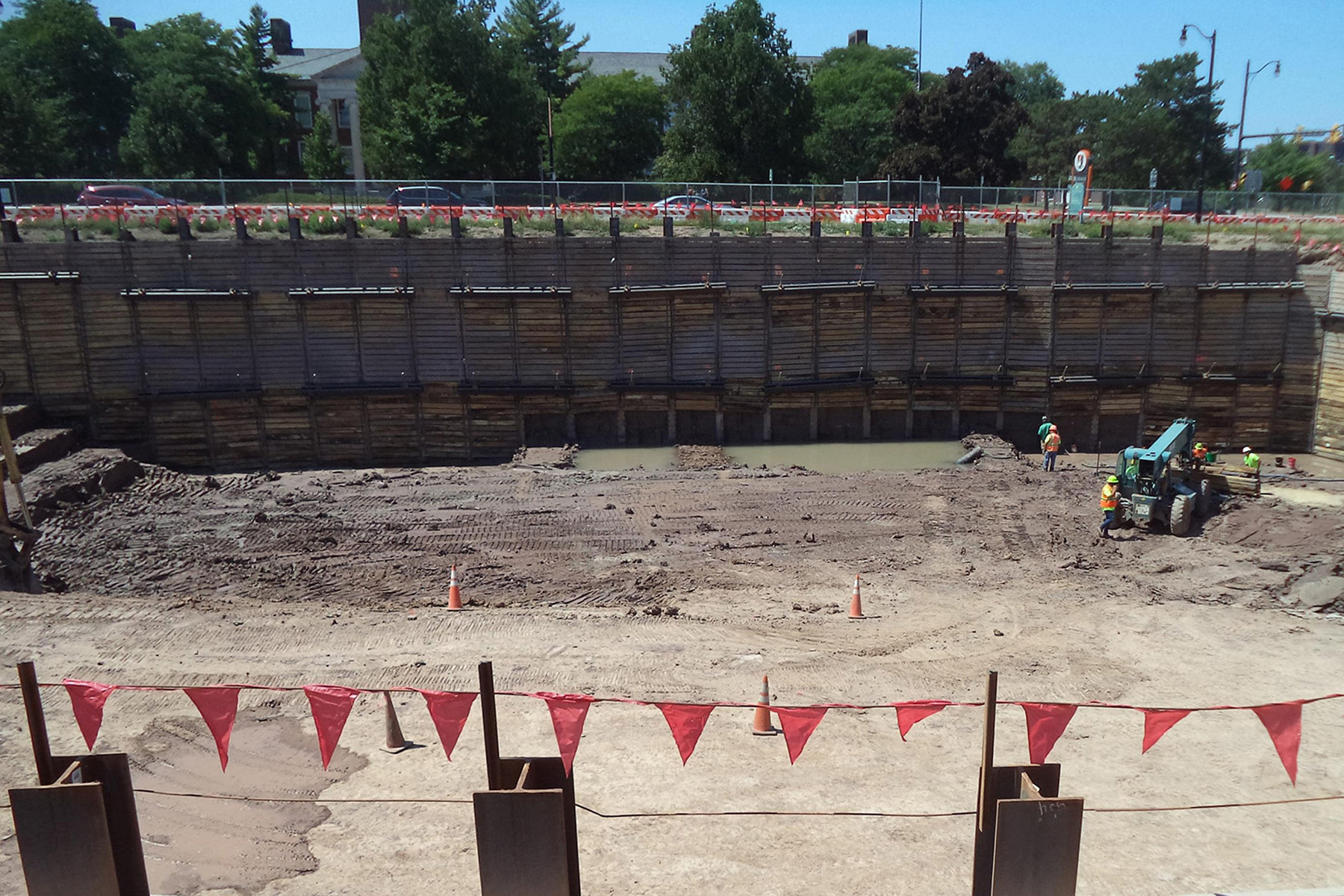 Construction workers and machinery are seen in a deep excavation.