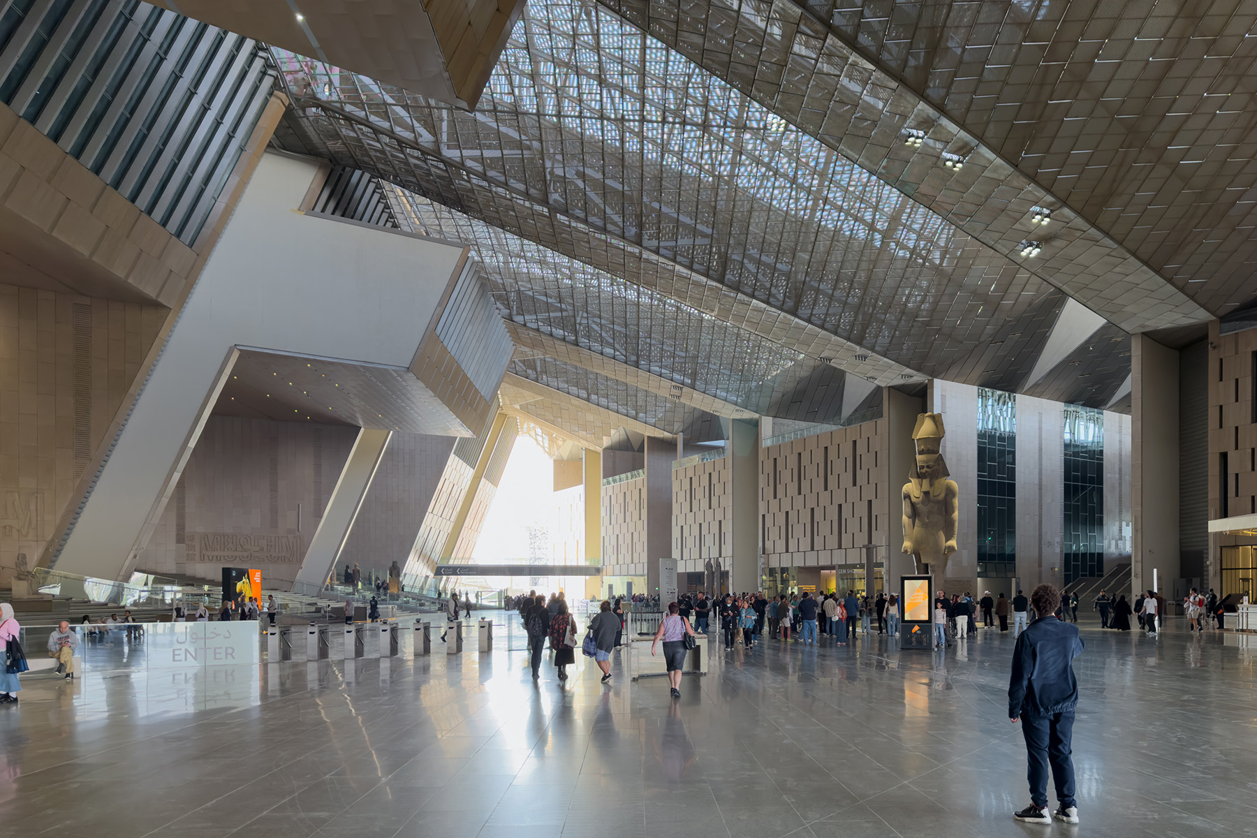 Photograph shows the steel lattice like, reinforced-concrete roof above the entrance court of a museum.