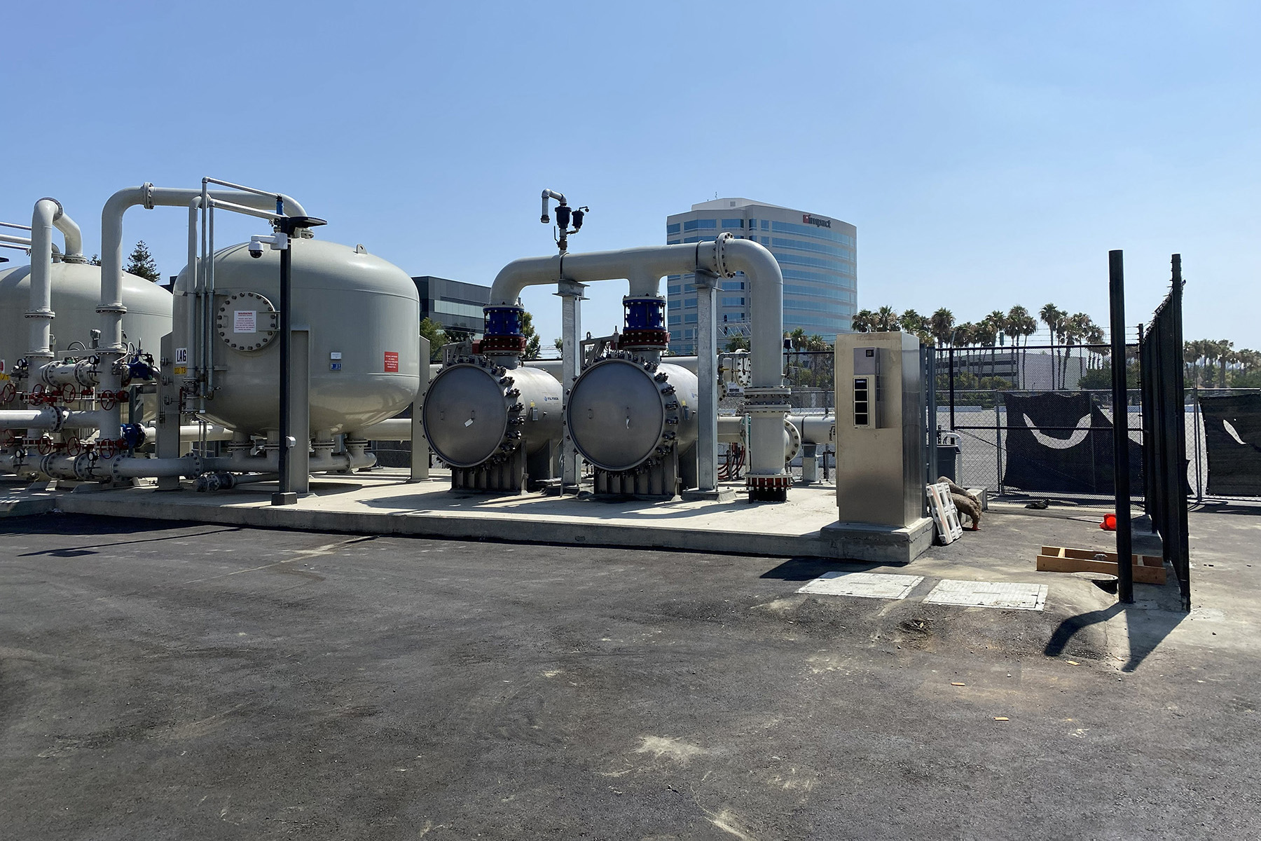 A photo shows outdoor tanks, pipes, and other equipment. 