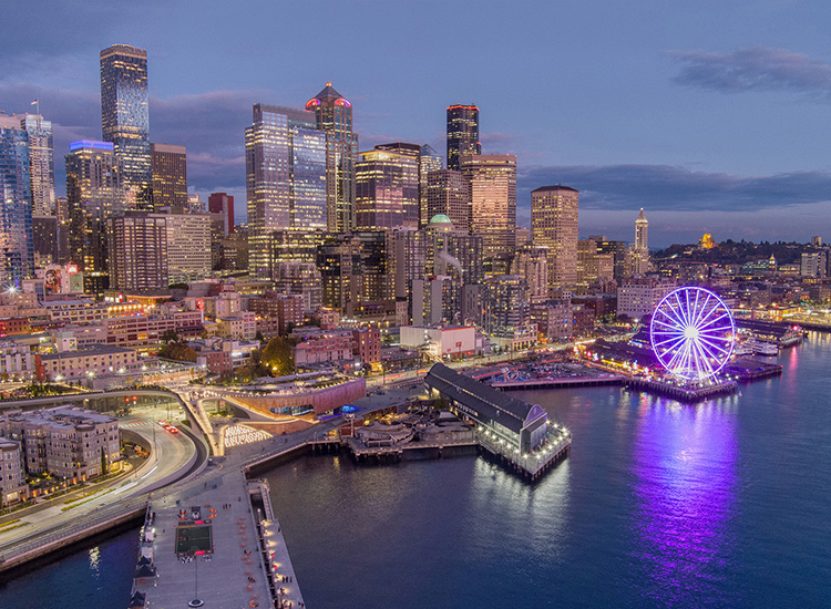 The photo shows the Seattle skyline and the new waterfront park illuminated at night. 