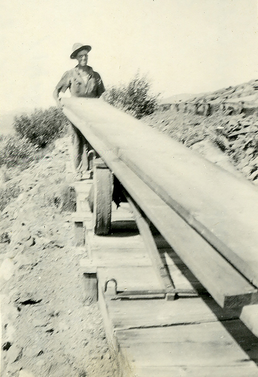 Image shows a man holding a long wooden plank. 